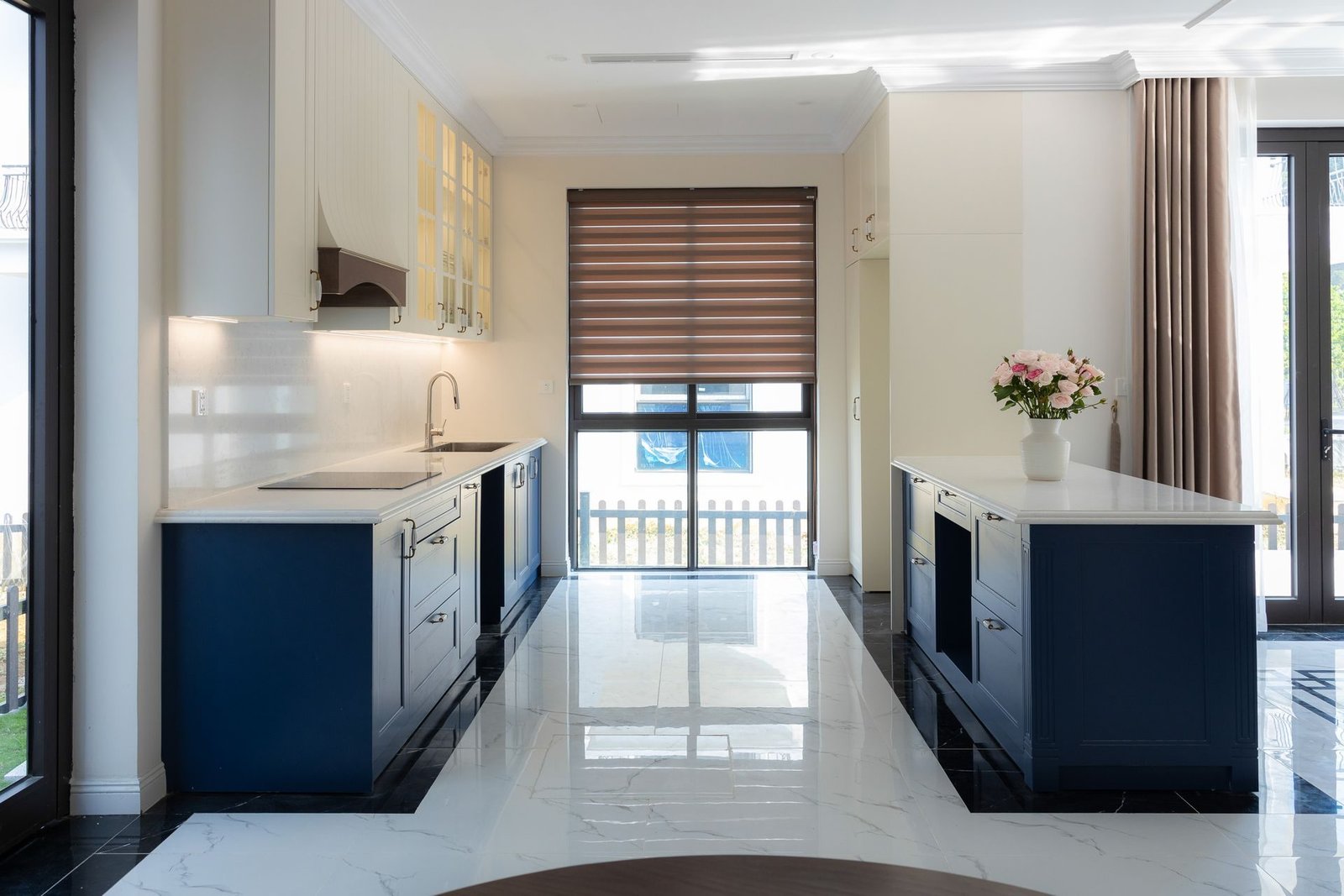 A bright renovated kitchen with blue cabinets and a marble floor