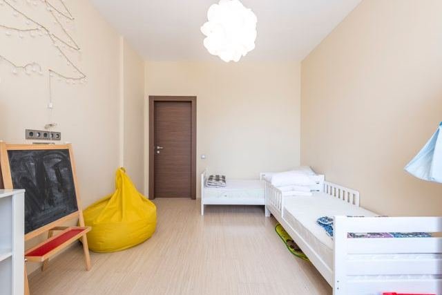 A child's bedroom with two white beds and a chalkboard
