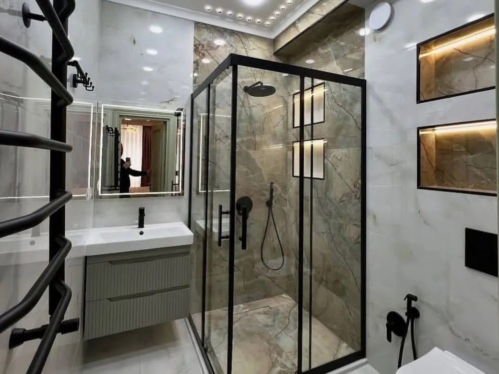 A finished bathroom with a glass shower and marble tiles