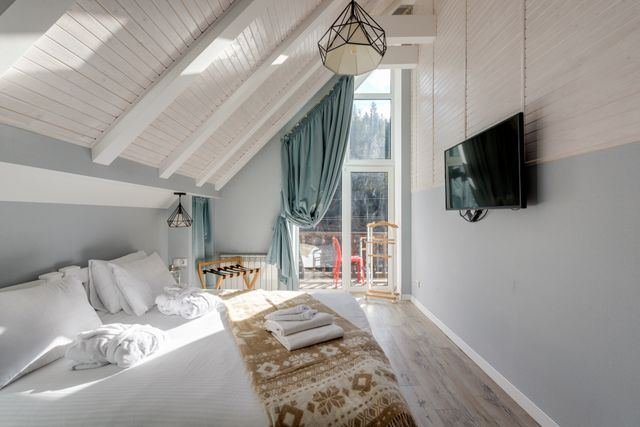 A loft bedroom with a sloped white timber ceiling