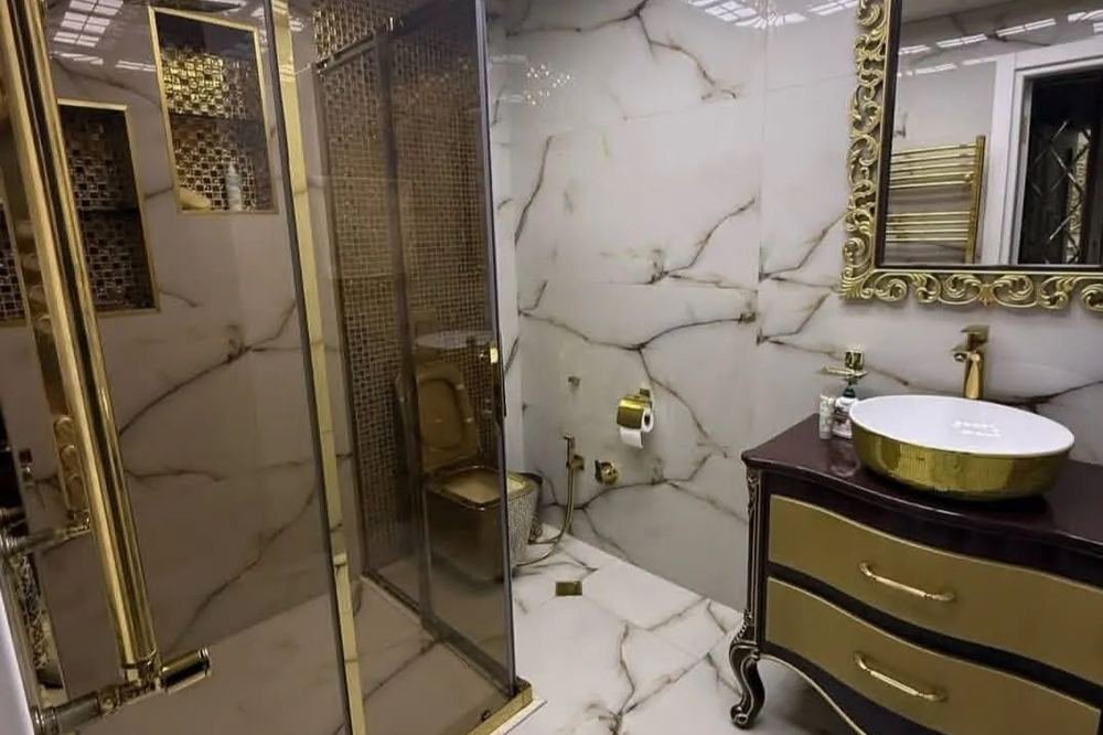 A marble bathroom with gold fittings and a gold-framed mirror