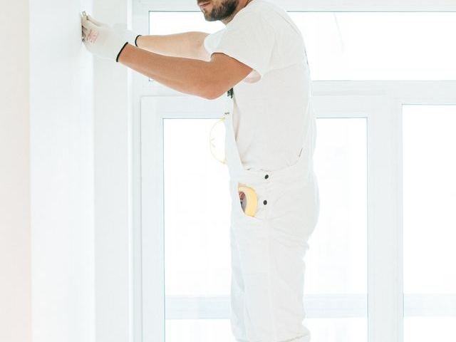 A plasterer on stilts smoothing a wall