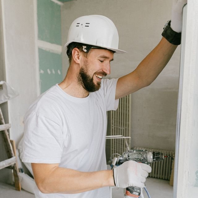 A plasterer smiling while working on a wall