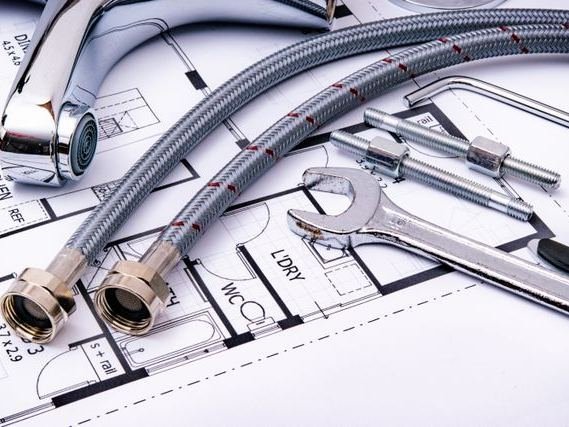 Plumbing hoses, a tap and a wrench laid on a floor plan