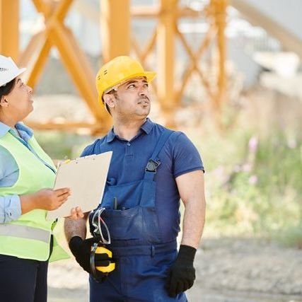Two site workers checking plans on a clipboard
